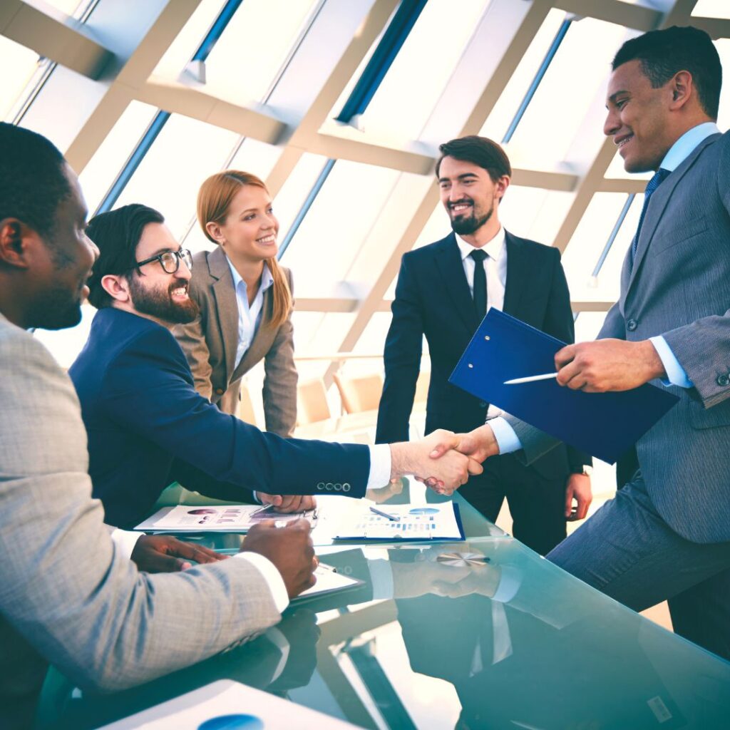 group of business people with two shaking hands over a table